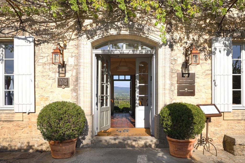 Überwucherter Hoteleingang des Hôtel Crillon Le Brave, mit geöffneten Türen und Durchblick in die provenzialische Landschaft