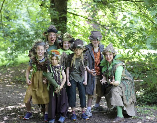 Kostümierte Erwachsene und Kinder im Wald