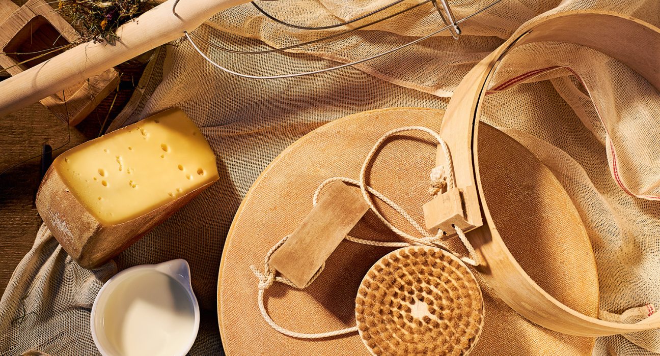 Käse mit Käseharfe und Käsebürste auf einem Tisch