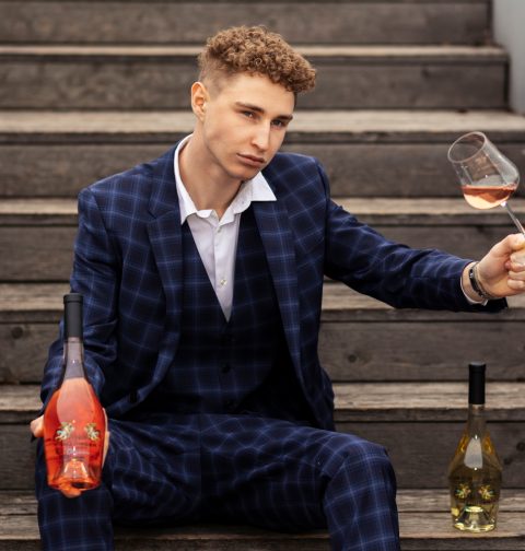 Leo Hillinger Junior mit einer Flasche Wein und einem Weinglas in der Hand