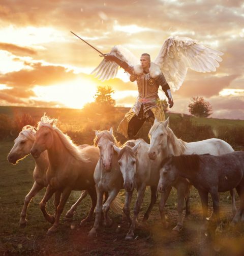 Ein Mann mit Engelsflügeln, Ritterüstung und einem Schwert mit sechs Pferden.
