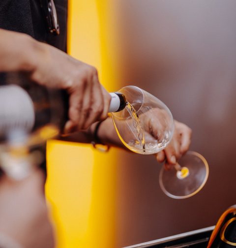 Wein wird aus Flasche in Weinglas eingeschenkt