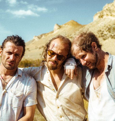 Drei Männer stehen in einer Wüste.