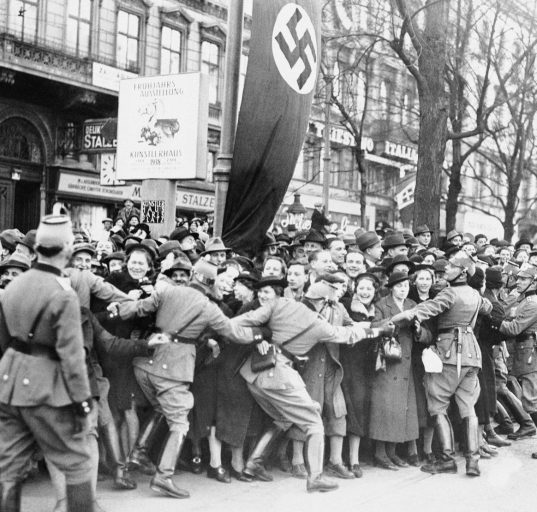 Historisches Foto von Wien 1938: Menschenmenge, die Adolf Hitler begrüßen will, wird von Polizisten zurückgehalten
