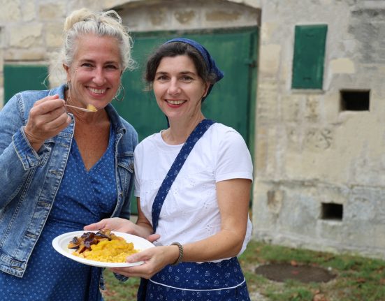 Zwei Damen posieren mit Teller in der Hand für diue Kamera