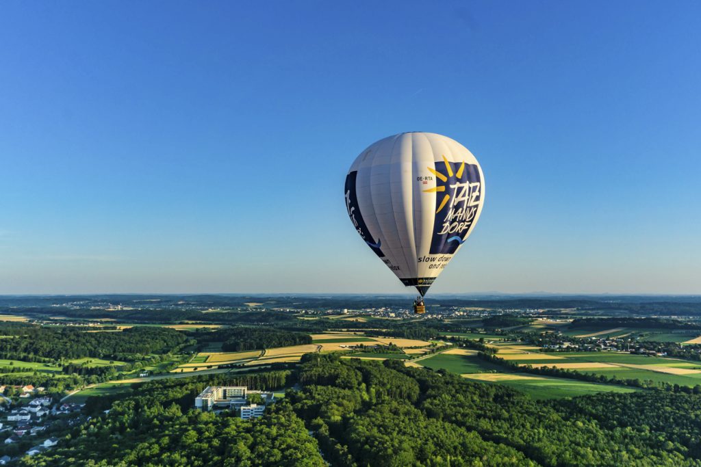Heißluftballon schwebt über dem grünen Wald