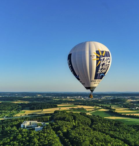 Heißluftballon schwebt über dem grünen Wald
